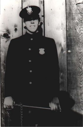 Son John Coleman Burroughs posing in his dad's police uniform