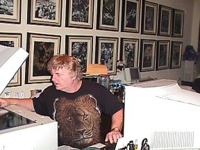 Bill using the office computer and scanner in front of a wall of Burian illustrations
